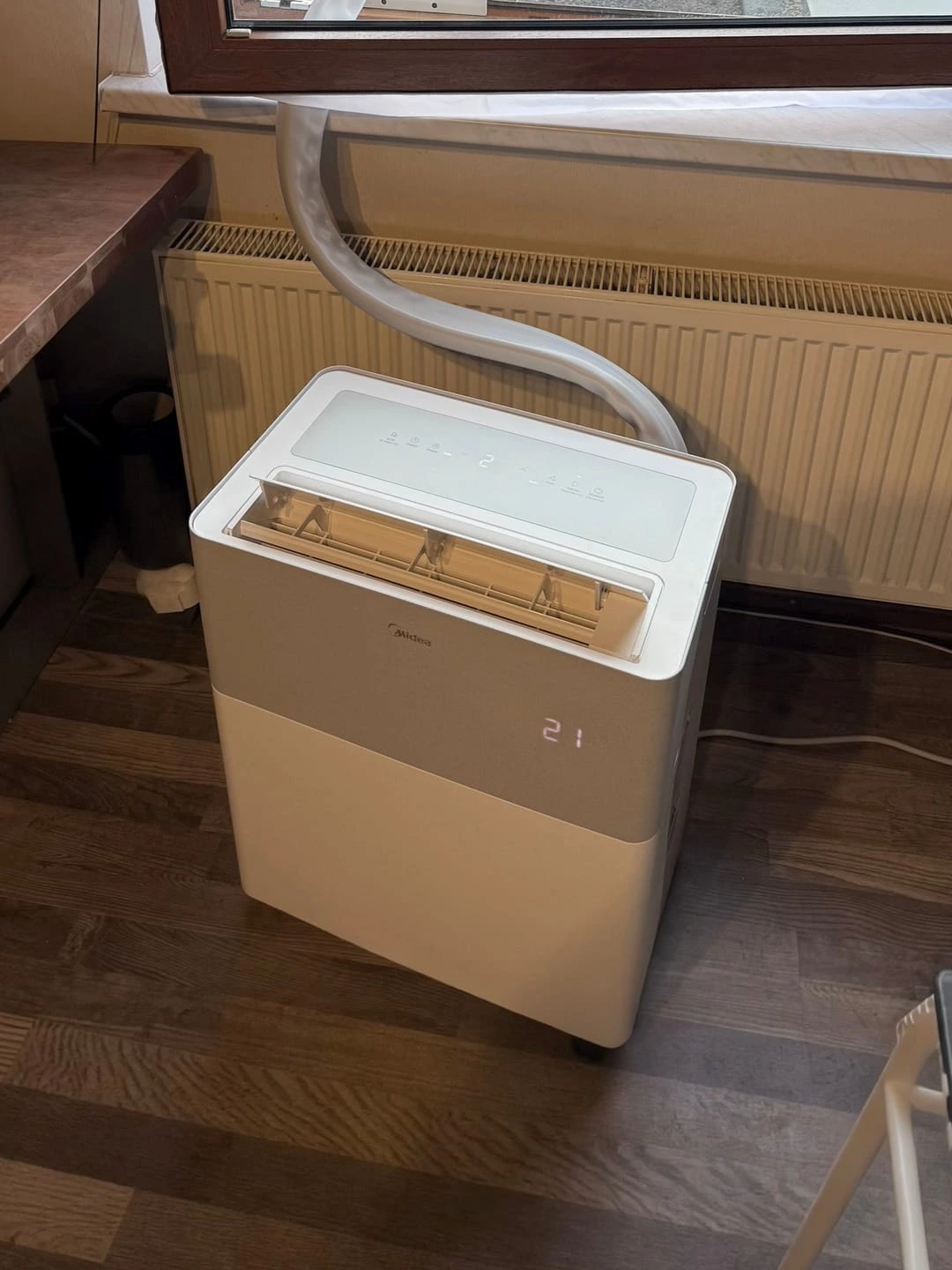 Le PortaSplit posé sur un parquet devant un radiateur, tuyau de liaison remontant vers la fenêtre