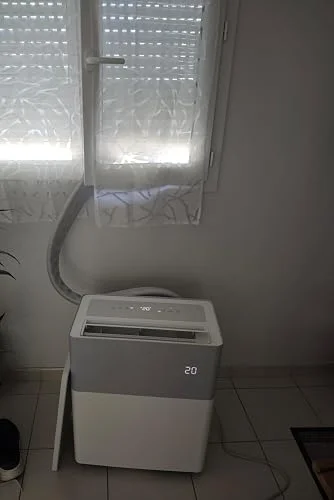 Le PortaSplit installé sous une fenêtre entrouverte, tuyau de liaison passant par l'ouverture