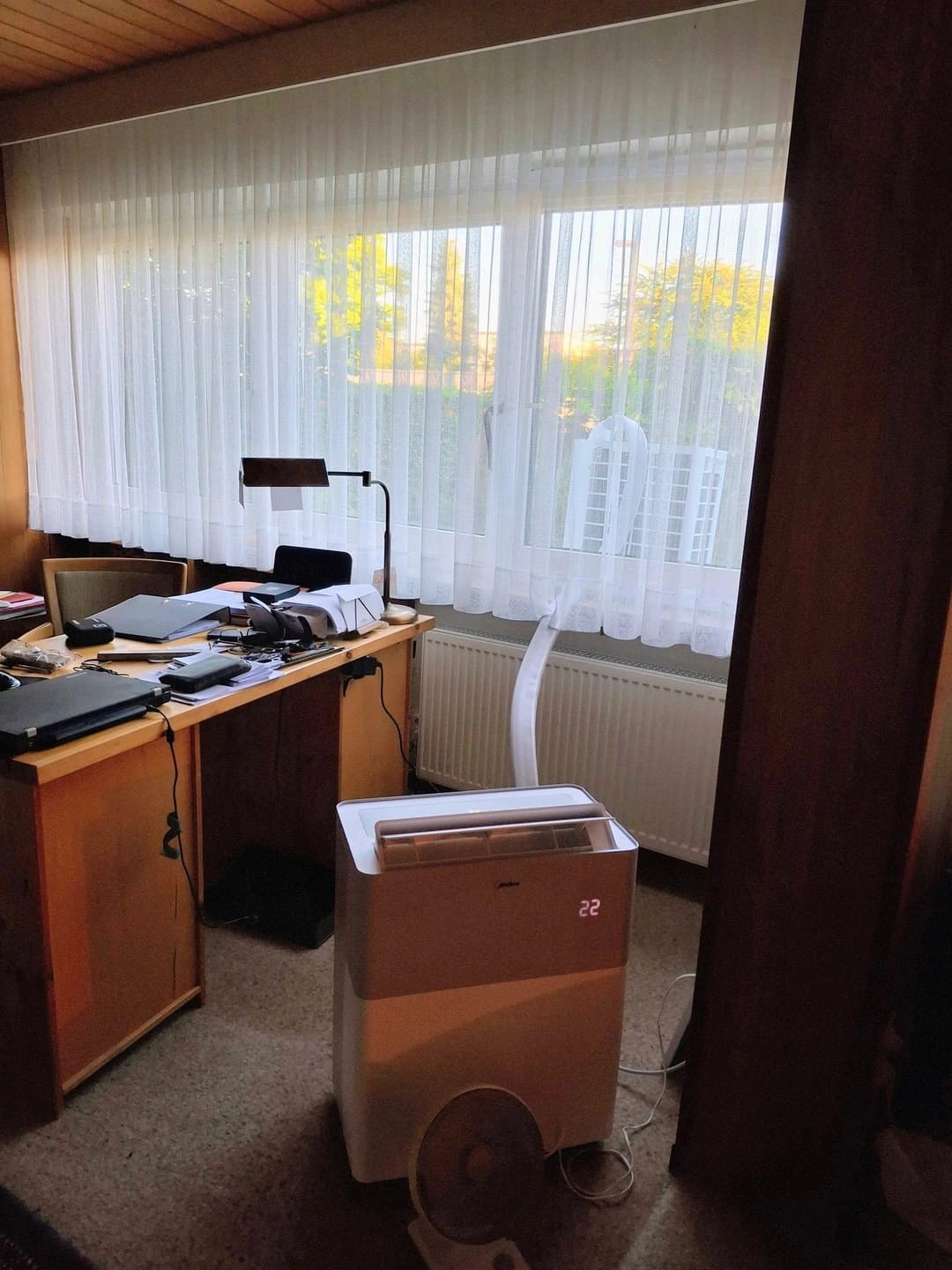 Le PortaSplit installé dans un bureau, devant une fenêtre à rideaux, tuyau de liaison remontant vers l'ouverture